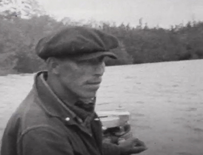 man in a cap holding the throttle of a boat on the water